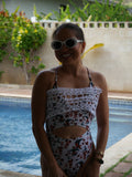 Woman in a white crochet coverup and sunglasses by a poolside