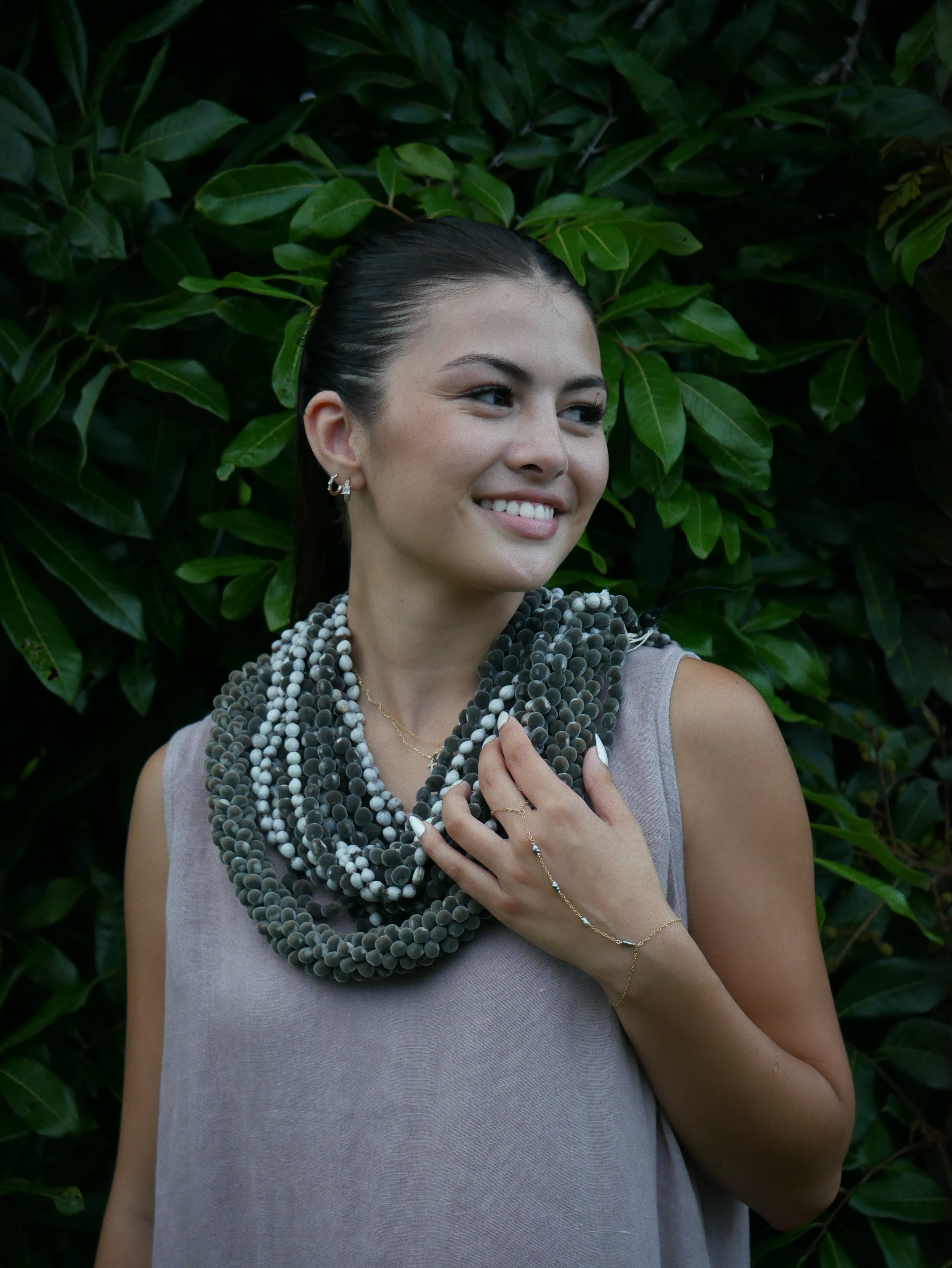 Model in a soft Kahoʻolawe-toned sleeveless linen midi dress with round neckline and pockets, wearing lei, photographed on a Hilo farm.