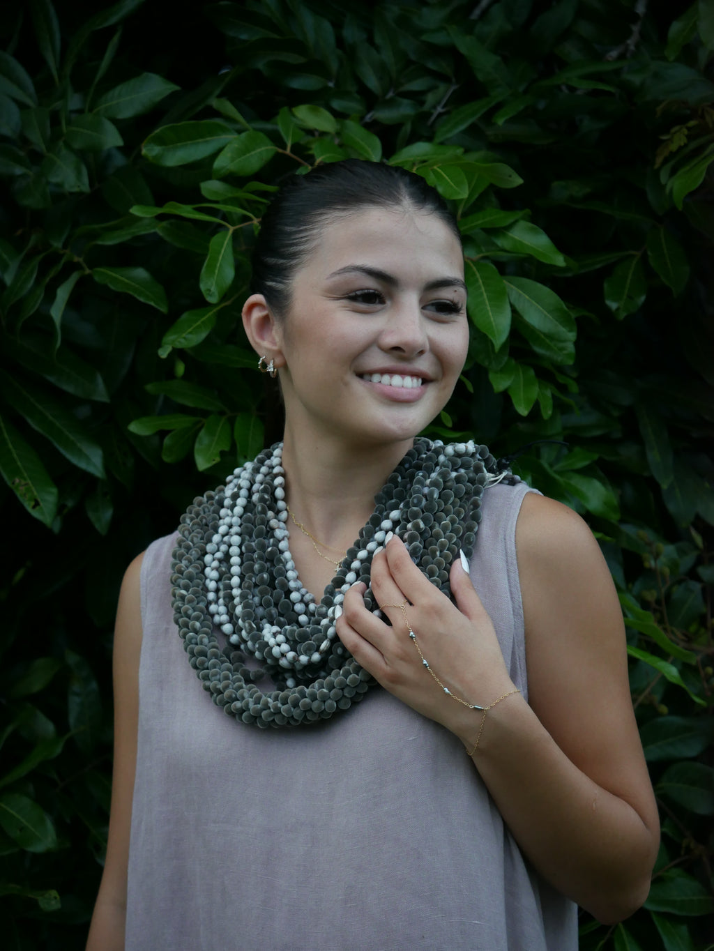 Model in a soft Kahoʻolawe-toned sleeveless linen midi dress with round neckline and pockets, wearing lei, photographed on a Hilo farm.