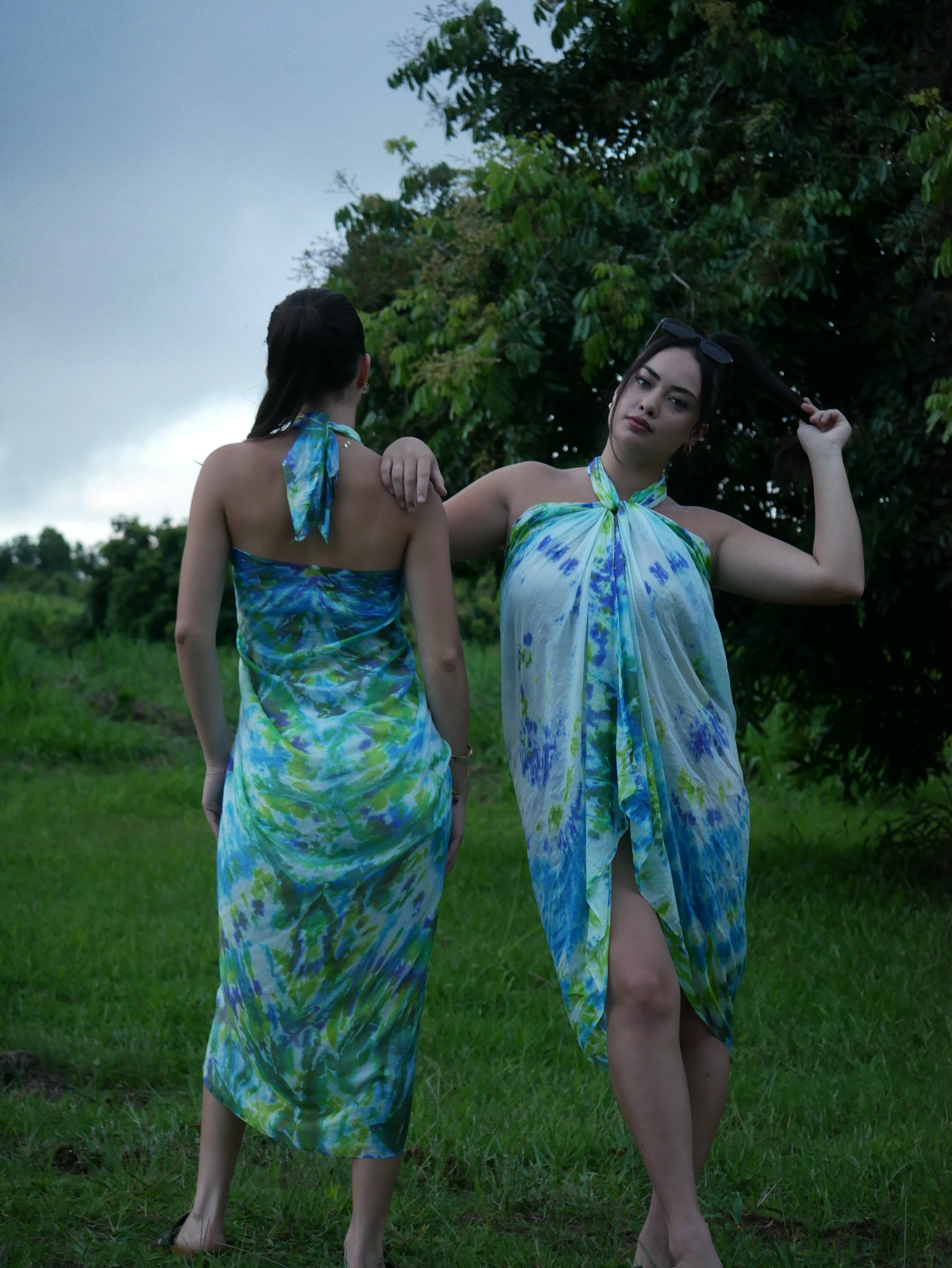 Models in green, blue, and navy shibori tie-dye silk wrap scarves, tied as pareo-style dresses, photographed at Olson Keolanui Farms in Hilo.
