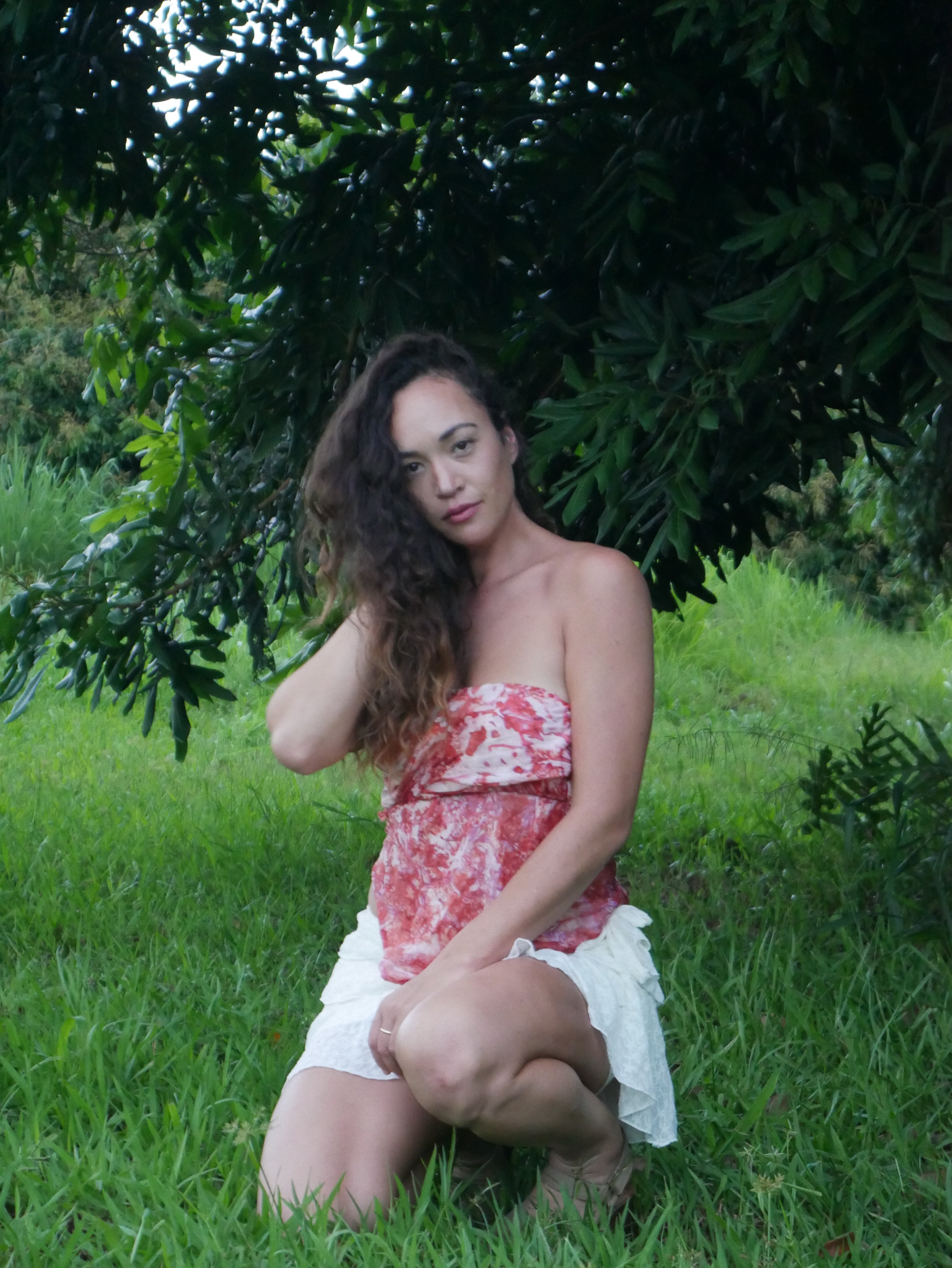 Model in a warm red shibori tie-dye silk wrap scarf, photographed at Olson Keolanui Farms in Hilo.