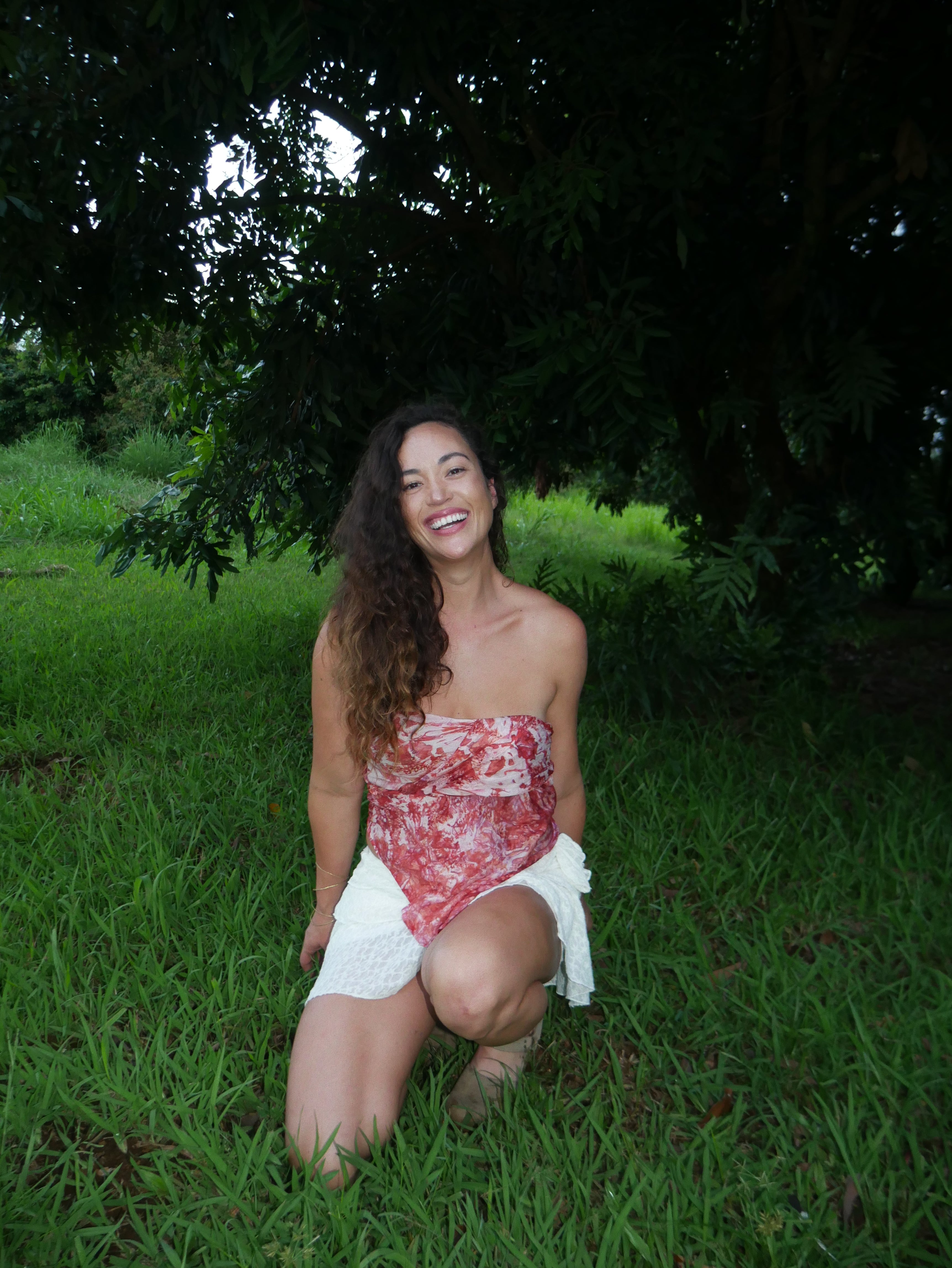 Model in a warm red shibori tie-dye silk wrap scarf, photographed at Olson Keolanui Farms in Hilo.
