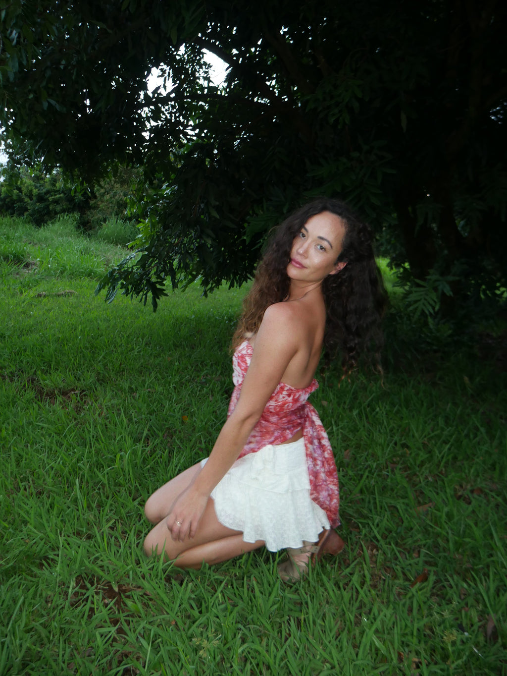Model in a warm red shibori tie-dye silk wrap scarf, photographed at Olson Keolanui Farms in Hilo.