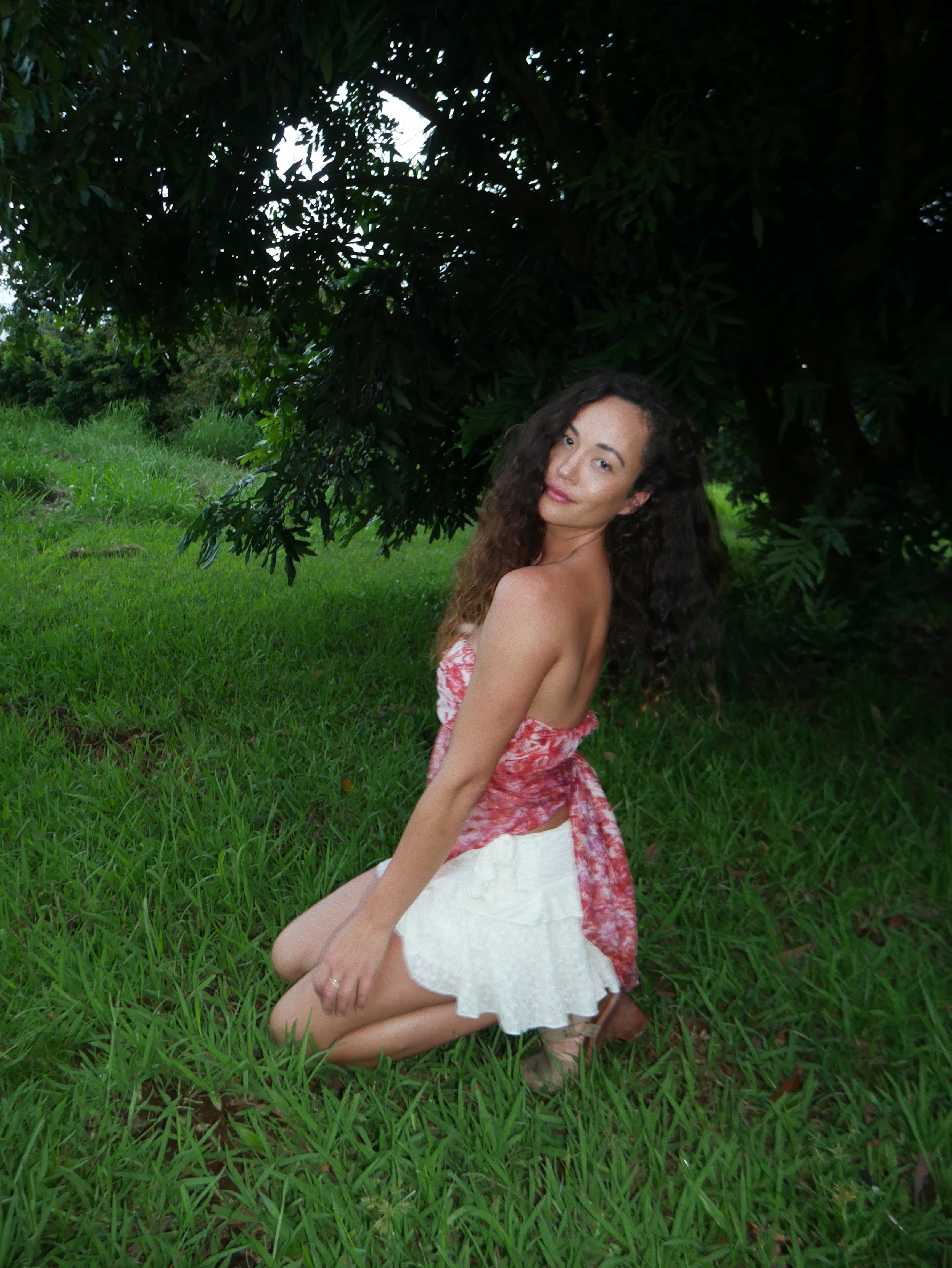 Model in a warm red shibori tie-dye silk wrap scarf, photographed at Olson Keolanui Farms in Hilo.
