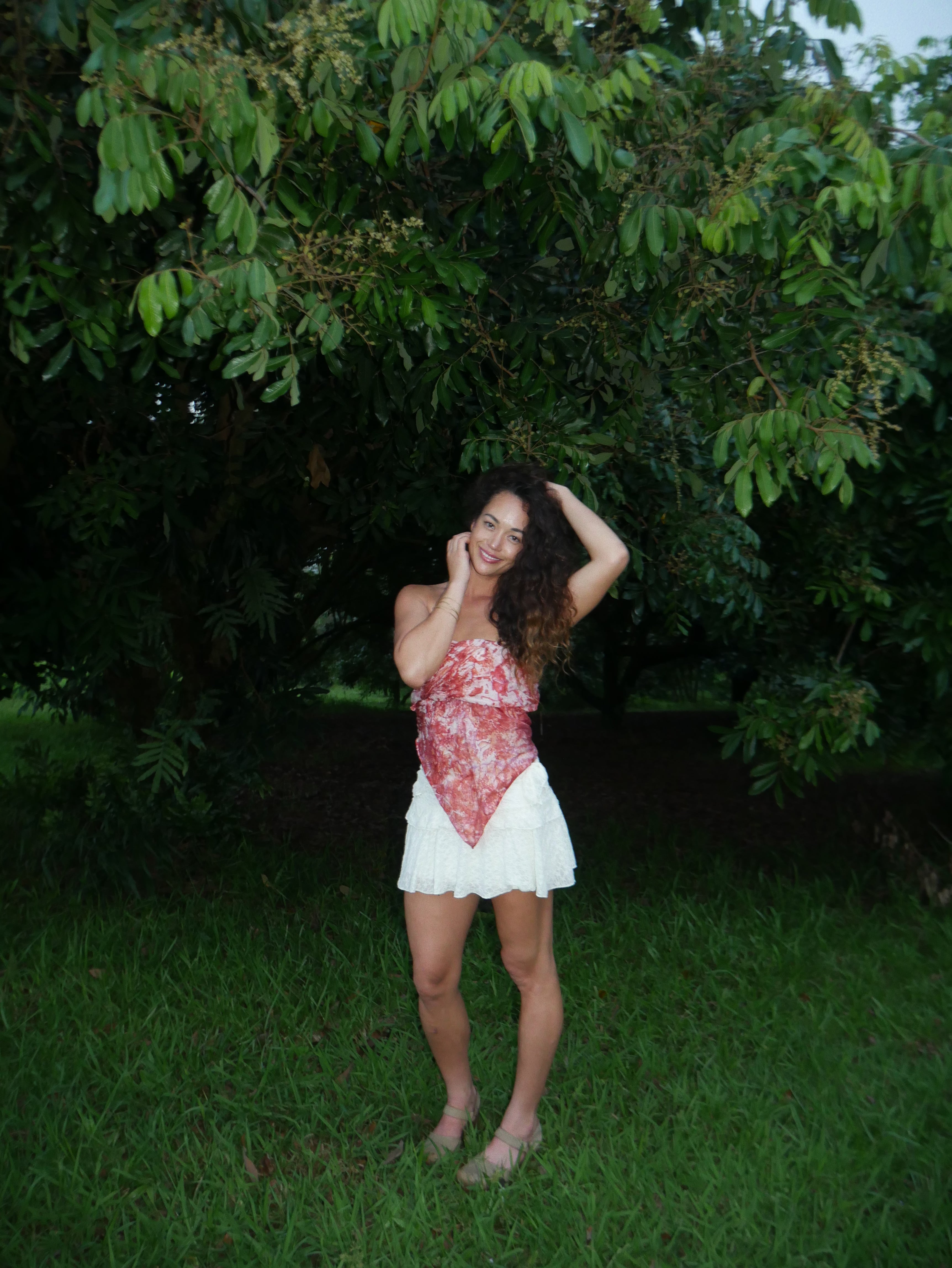 Model in a warm red shibori tie-dye silk wrap scarf, photographed at Olson Keolanui Farms in Hilo.